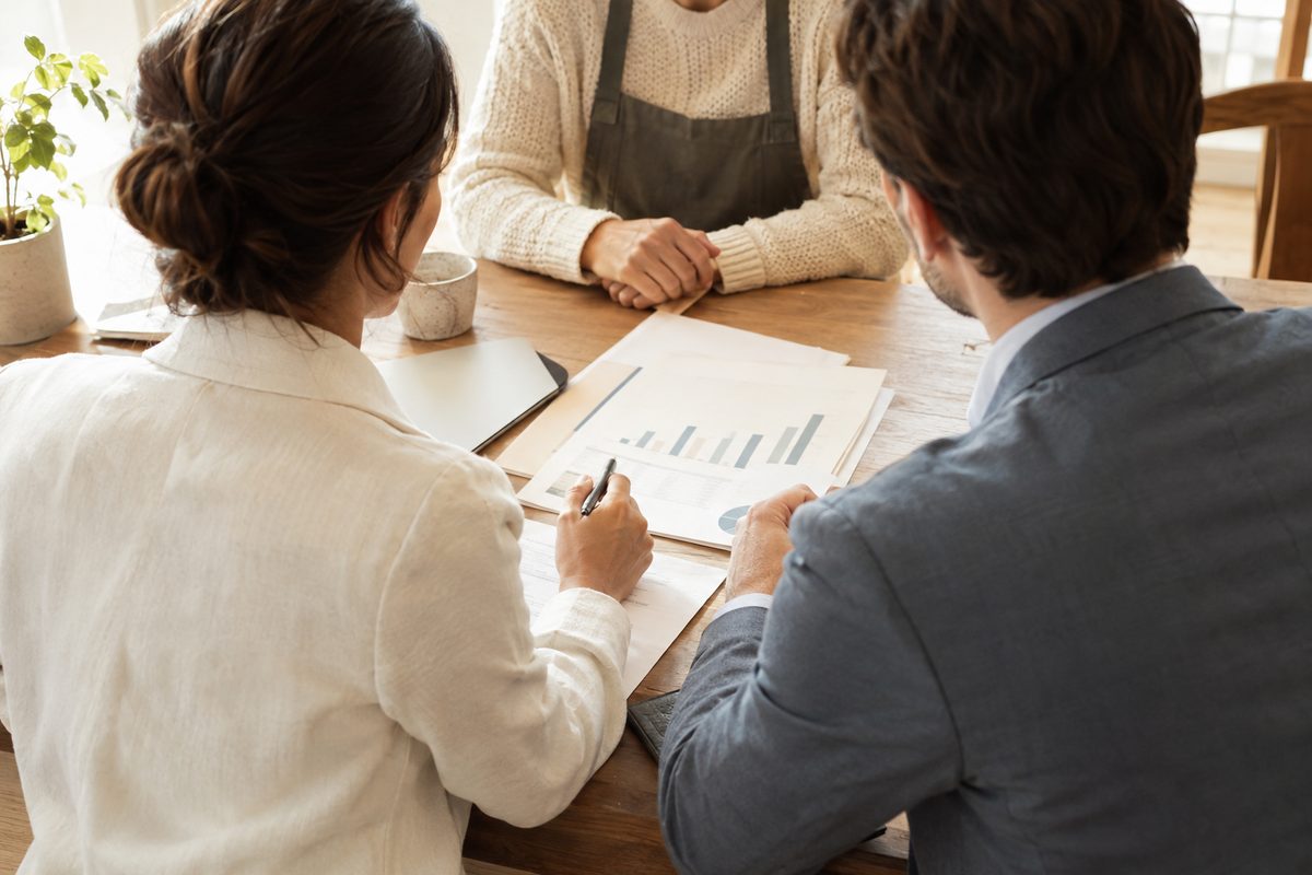 Consultants reviewing documents with a business owner at a wooden table